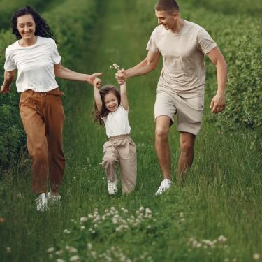 Joyful family enjoying a fun day outdoors in a green field, epitomizing togetherness and happiness.